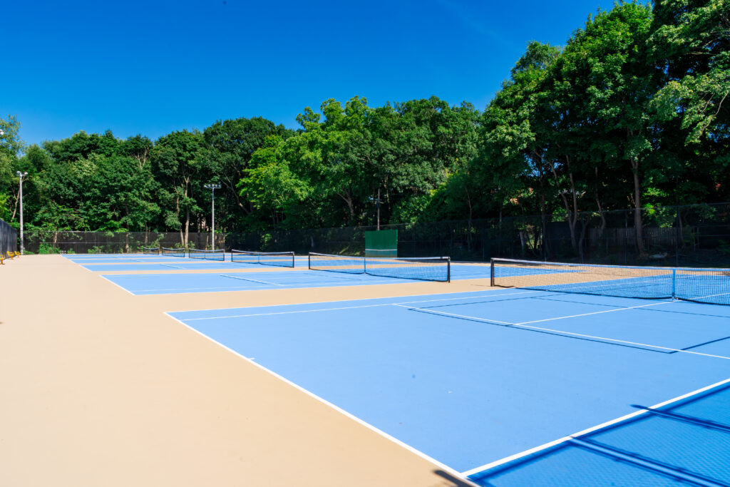 Outdoor tennis courts with a blue surface.