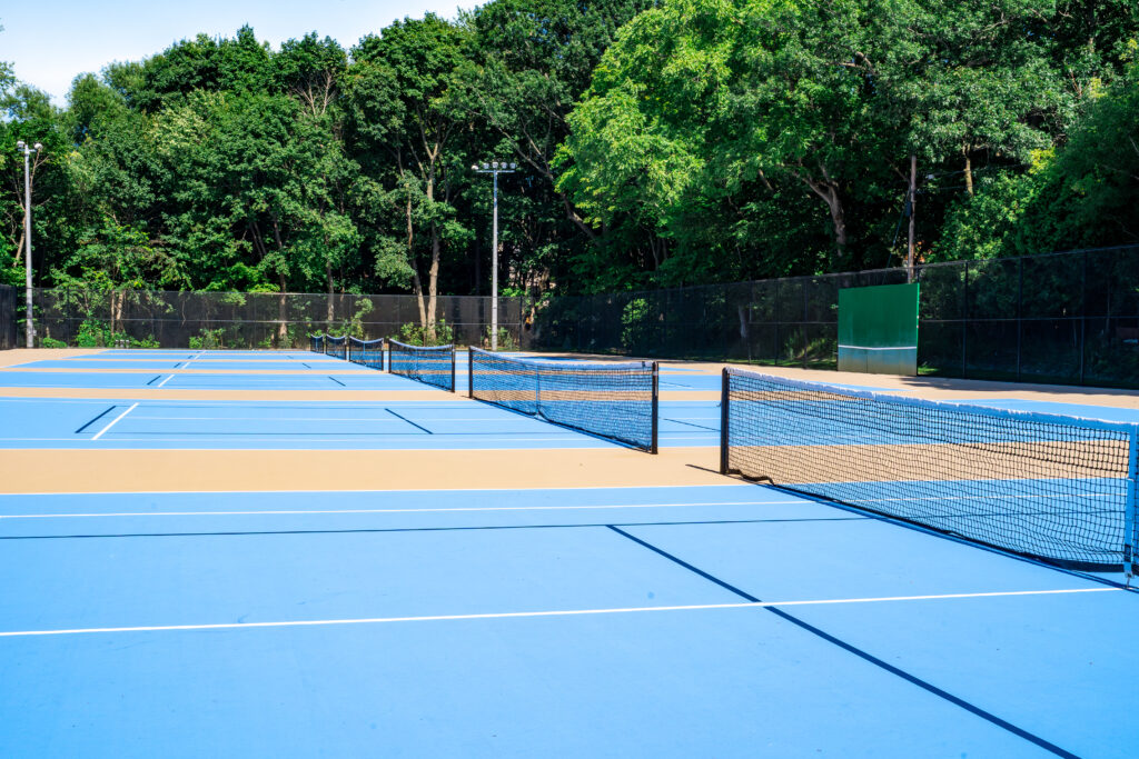 Outdoor tennis courts with a blue surface.