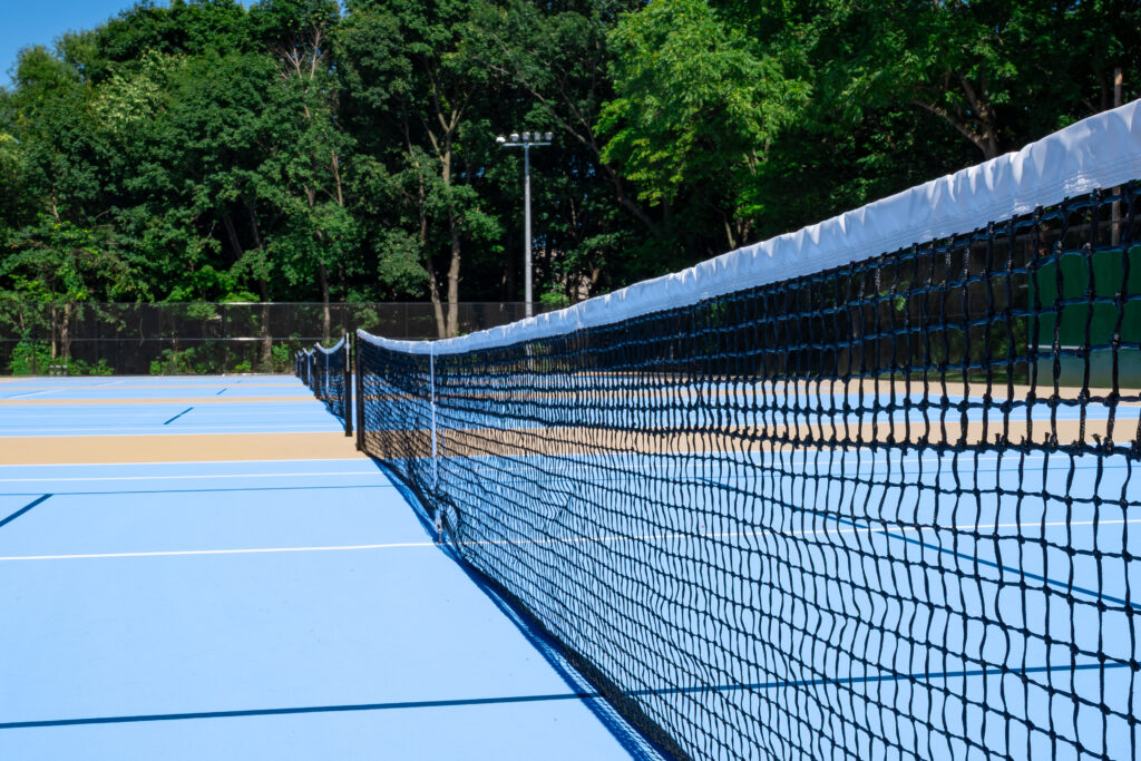 Close up view of nets on blue-topped tennis courts.