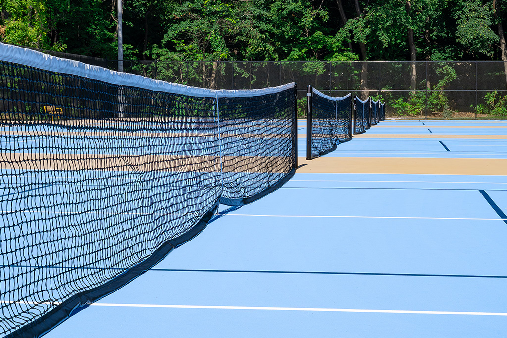 Close up view of nets on blue-topped tennis courts.