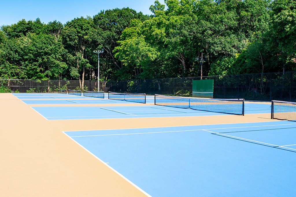 Outdoor tennis courts with a blue surface.