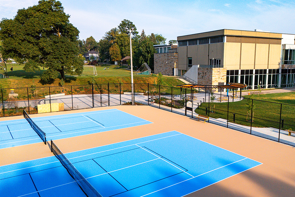 A view of tennis courts with a blue surface looking towards the Athletic Centre.